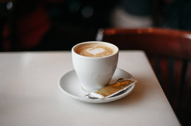 Eine Tasse Kaffee auf einem Tisch mit gezeichnetem Herzen  - Foto, Bild