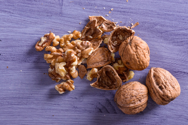 Closeup of cracked walnuts on purple table - Photo, Image