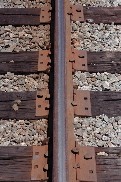 Demiryolunun bir parçası, klempleri, çivileri ve kravatları yakından gören bir pist. - Fotoğraf, Görsel