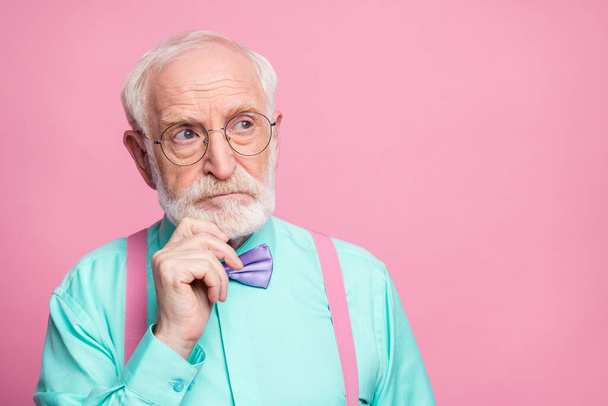 Closeup photo of attractive stylish grandpa holding hand on chin look up empty space minded wear specs mint shirt suspenders violet bow tie isolated pink pastel color background - Фото, зображення