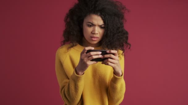 Young african displeased woman isolated over dark red burgundy background watch disgusting videos by mobile phone - Materiaali, video