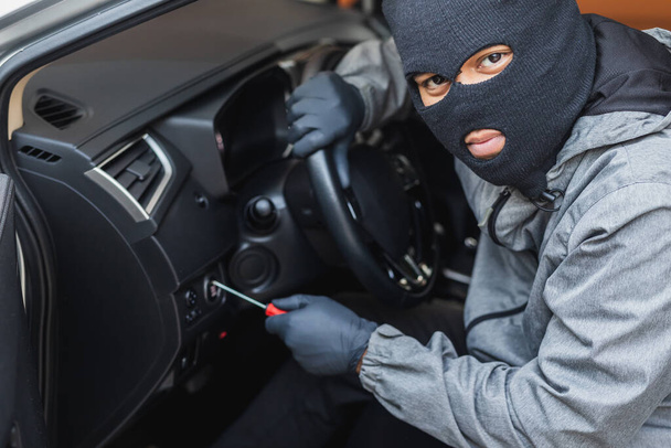 A tolvaj csavarhúzót használ, hogy ellopjon egy autót. A gépjármű-biztosítás fogalma. - Fotó, kép