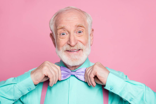 Close up photo of funny grandpa hold hands buttoning necktie positive emotions before senior meeting party wear mint shirt suspenders violet bow tie isolated pink pastel background - Foto, Bild