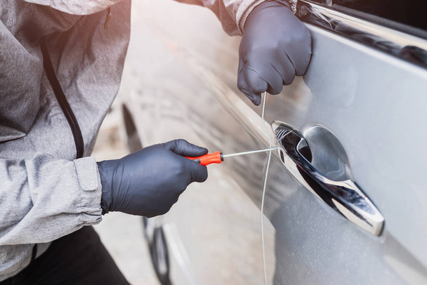 Złodziej używa śrubokrętu kradnącego samochód przy klamce. Koncepcja ubezpieczenia pojazdu. - Zdjęcie, obraz