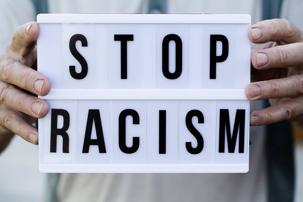 STOP RACISMメッセージ付きライトボックスを保持老人 - 写真・画像