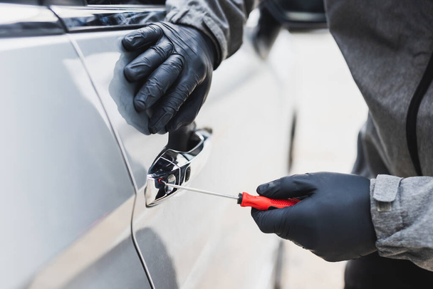 The thief uses a screwdriver Stealing a car at the door handle. The vehicle insurance concept. - Фото, зображення
