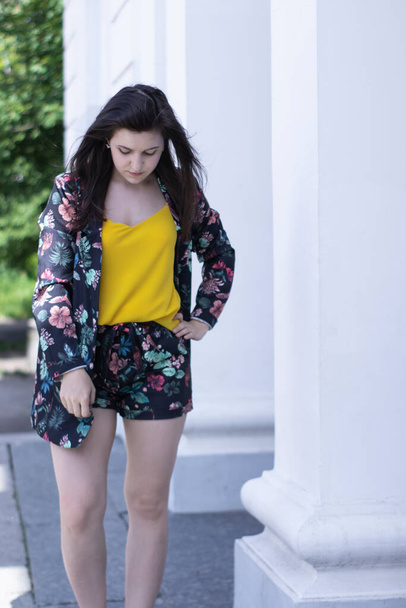 Attractive young brunette woman in yellow t-shirt and flowery shorts costume. copy space. - Fotó, kép