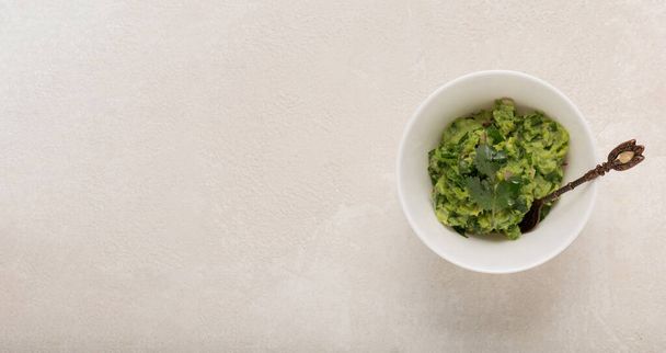 Mexican guacamole sauce in a white bowl on a concrete background, top view - Fotoğraf, Görsel