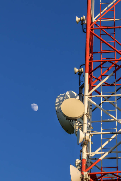 Zbliżenie wieży transmisyjnej pełnej urządzeń z niebieskim niebem w tle. - Zdjęcie, obraz