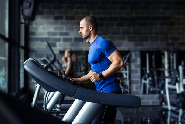 Young man in sportswear running on treadmill at gym. - Φωτογραφία, εικόνα
