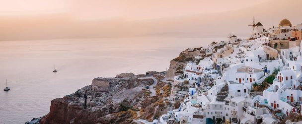 Santorini Oia Grecja Europa, zachód słońca w białej wiosce Oia Santorini ze starymi niebiesko-białymi greckimi kościołami o zmierzchu - Zdjęcie, obraz