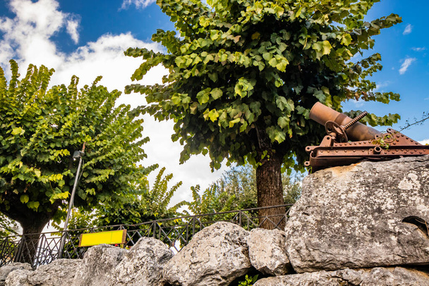 Bellegra, Rzym, Lacjum, Włochy - Mały publiczny ogród w centrum Bellegry, otoczony starożytnymi wielokątnymi murami miasta. Drzewa i duże bloki kamienia. - Zdjęcie, obraz