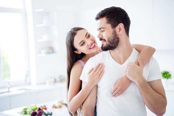 Portrait of positive charming spouses couple woman piggyback hug man look enjoy rest relax date stay home quarantine in house kitchen indoors - Foto, afbeelding