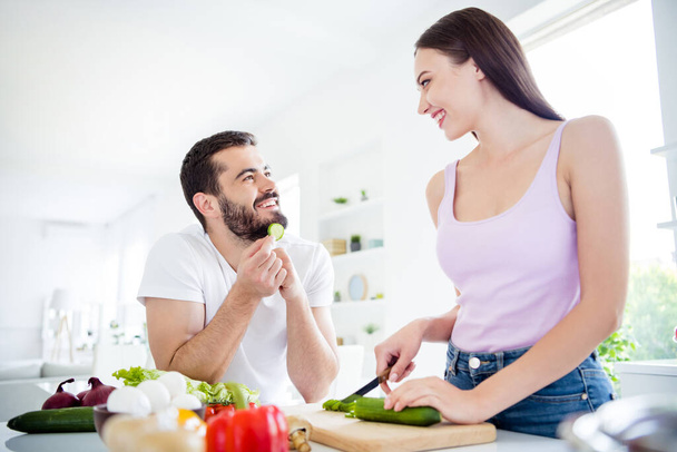 Portrait of two people have stay home quarantine prepare fresh veggie dish woman cut chopping board cucumber man look eat slice in house indoors - Foto, imagen