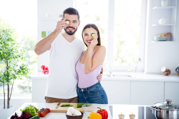 Portrait of positive two people spouses man woman hug close cover eyes enjoy quarantine evening family day dish veggie salad preparation in kitchen house indoors - Photo, image