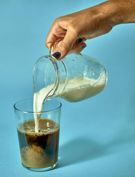 Hand gießt Milch in Kaffee - Foto, Bild