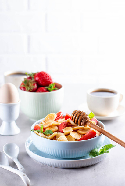 Pannenkoeken, mini pannenkoeken in een kom met aardbeien. Lekker ontbijt - Foto, afbeelding