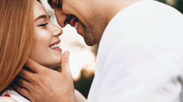 Photo rapprochée d'une femme caucasienne aux cheveux roux et aux taches de rousseur vêtue d'un vêtement blanc et son amant embrassant et embrassant
 - Photo, image