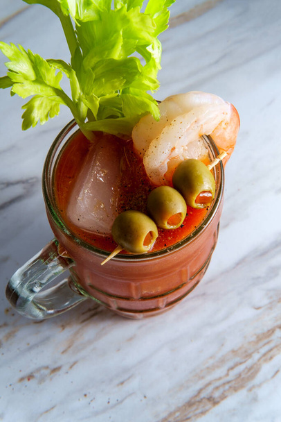 Bloody Mary vodka cocktail in a beer stein with shrimp garnish on marble kitchen table - Photo, Image