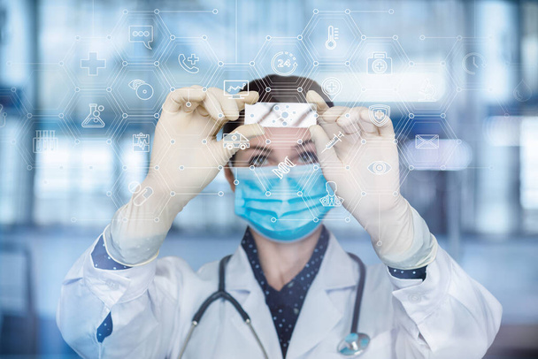 Η ιδέα της διεξαγωγής ιατρικών πειραμάτων. Ο γιατρός εξετάζει το δείγμα στο φόντο των ιατρικών εικονιδίων. - Φωτογραφία, εικόνα