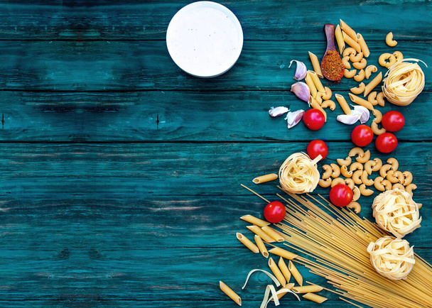Spagetti, tagliatelle, pasta, kirsikkatomaatit, valkoinen souse tummalla puupohjalla - Valokuva, kuva
