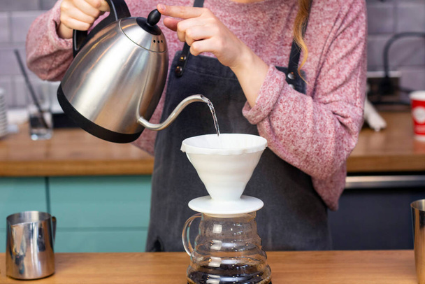 barista makes espresso using a funnel. The process of making coffee in the prover. Spilling coffee through the filter funnel from the kettle. - Foto, Imagen