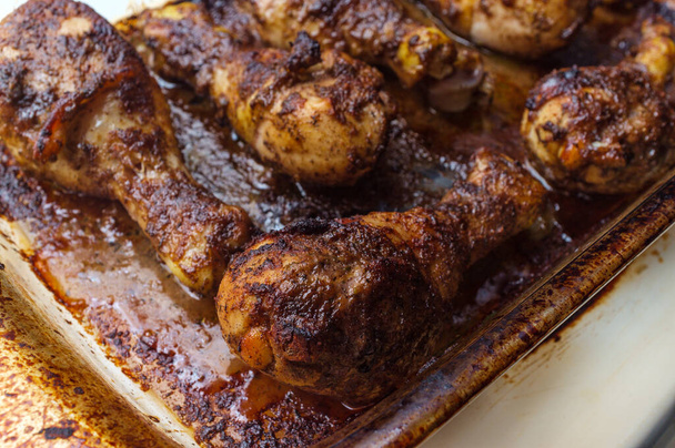 Cooking baked authentic spicy Jamaican jerk chicken legs in oven using casserole dish - Photo, Image