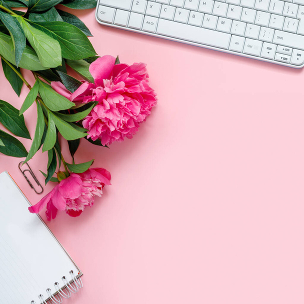 Laptop, accessories and bouquet of beautiful peonies on pink background. Flat lay of working place.  - Valokuva, kuva