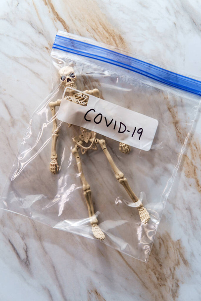 Toy csontváz műanyag zacskóban felcímkézett COVID-19 jelképezi a halálos áldozatok száma a koronavírus - Fotó, kép