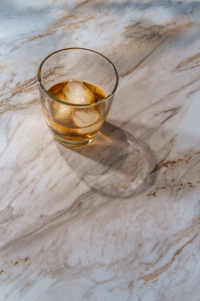 Whisky con hielo en vidrio de rocas en el mostrador de cocina de mármol
 - Foto, imagen