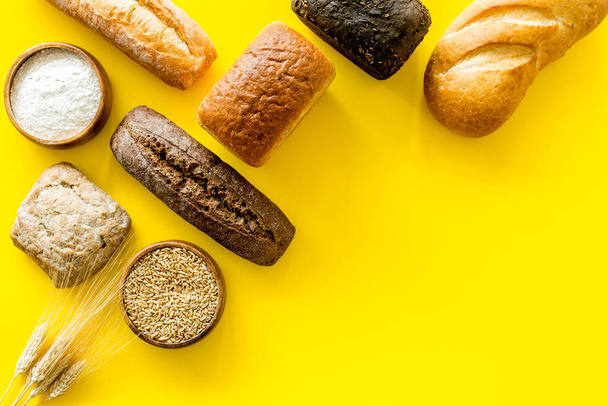 Bread with wheat ear and flour on yellow background. Top view - Фото, изображение