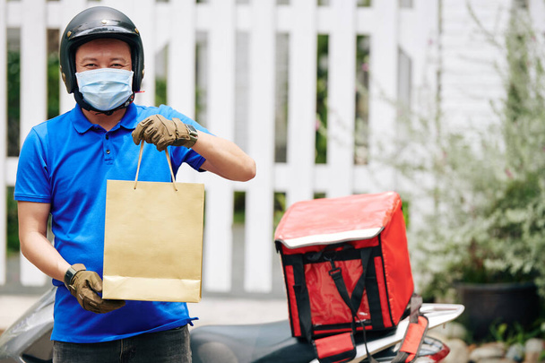 Retrato de correio alegre entregando pacotes com mantimentos frescos para clientes que ficam em casa durante a pandemia de covid-19
 - Foto, Imagem