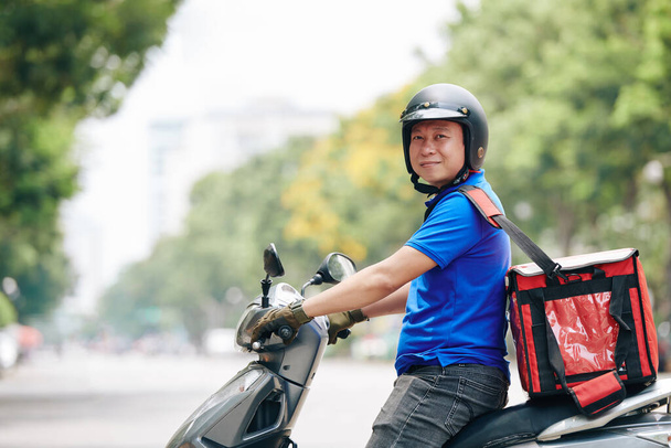 Retrato del alegre hombre vietnamita con gran bolsa de enfriamiento trabajando para el servicio de entrega
 - Foto, imagen