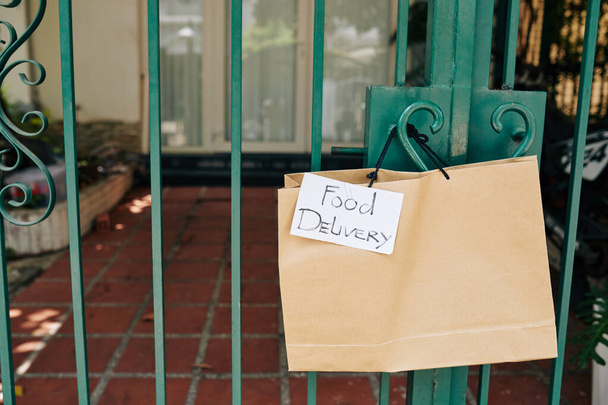 Papier torba z żywnością wiszące na uchwycie bramy klienta zamówił kontakt bezpłatna dostawa do jego domu - Zdjęcie, obraz