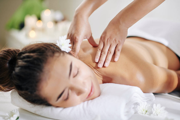 Immagine ravvicinata di massaggiatrice massaggiando collo e spalle di giovane bella donna
 - Foto, immagini