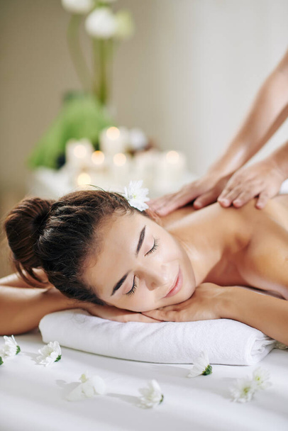 Красивая молодая женщина получает профессиональный массаж спины в спа-салоне с увлажняющими маслами
 - Фото, изображение