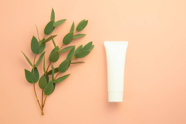Natural organic cosmetic skincare white tube for mock up and fresh leaves on beige background - Fotó, kép