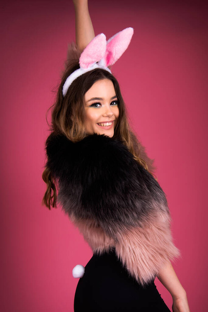 Tavşan partisi kostümü giyen sevimli bir kız, arka planda izole edilmiş, pembe sahte kürk moda moda parti tarzı. - Fotoğraf, Görsel