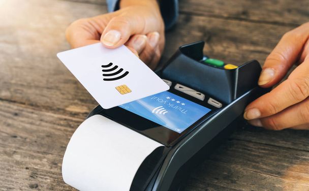 Концепция бесконтактных платежей, женщина-клиент, держащая кредитную карту рядом с NFC технологии на счетчике, клиент сделать оплату транзакции счет на терминале RFD кассир машины в ресторане или магазине, закрыть обзор
 - Фото, изображение