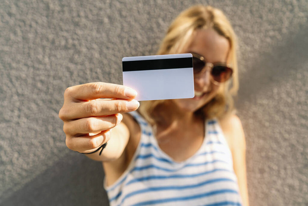 Portré egy csinos fiatal nőről pulóverben, aki hitelkártyát tart az arcához. copyspace az Ön egyedi szövegéhez.  - Fotó, kép
