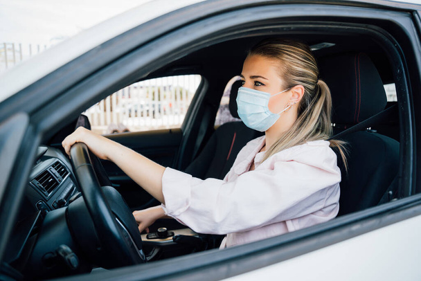  Woman with face mask driving her car during coronavirus pandemic - Foto, imagen