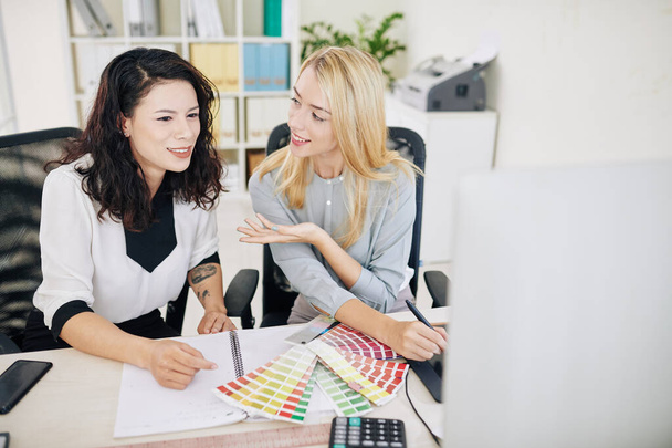 Позитивные женщины-дизайнеры UX и UI сидят за рабочим столом и обсуждают цветовую схему нового проекта
 - Фото, изображение