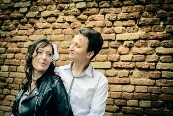 unusual wedding couple near a brick wall - Valokuva, kuva