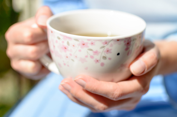 Žena drží šálek horkého čaje ve svých rukou na slunci - Fotografie, Obrázek