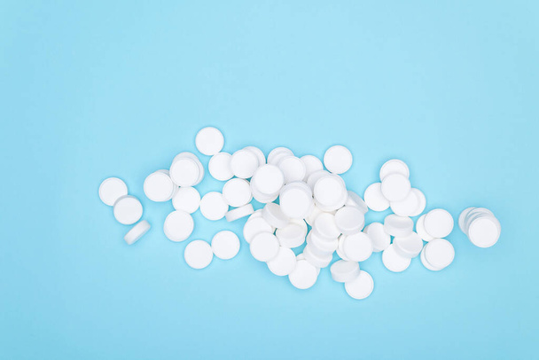 White pills on blue background.Background of large white tablets on blue paper. Pile of pills. - Фото, изображение