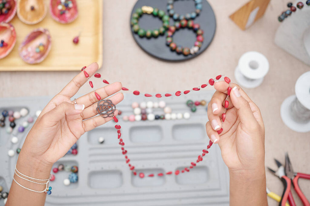 Manos de mujer sosteniendo hermoso collar hecho con piedras de jasma rojo natural
 - Foto, imagen