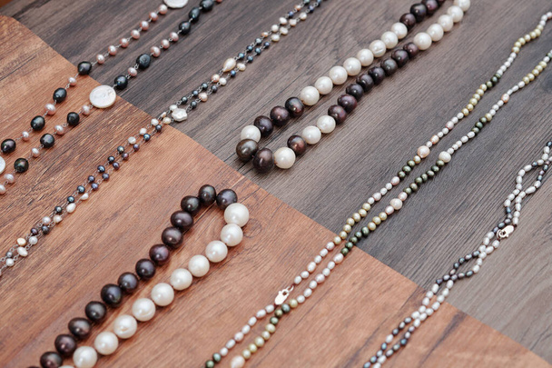 Hermosos collares hechos a mano con varias piedras preciosas blancas y marrones en la mesa de madera
 - Foto, imagen