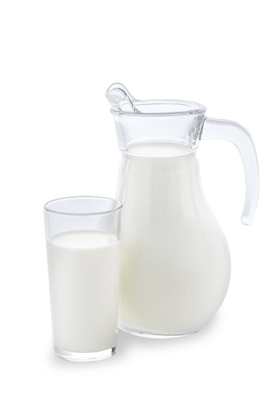 A jug and a glass completely filled with fresh cow milk stand on a clean white background. - Фото, зображення