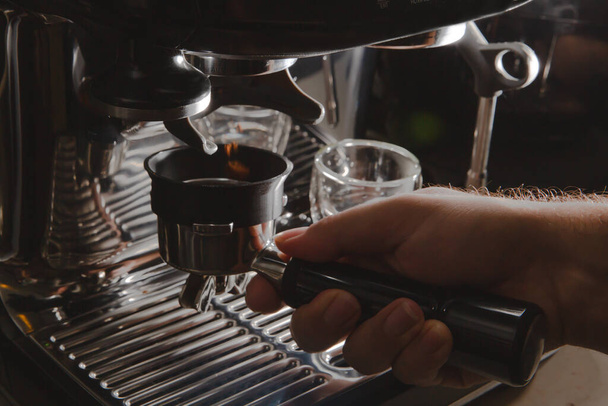 Close up shot of a barista's hand grinding coffee beans to brew espresso, close up manual espresso machine - Photo, Image