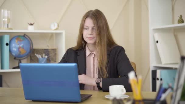 Redhead Caucasian woman sitting in front of laptop and talking. Portrait of beautiful female freelancer working remotely. Isolation, freelance, lifestyle, remote work, business. - 映像、動画